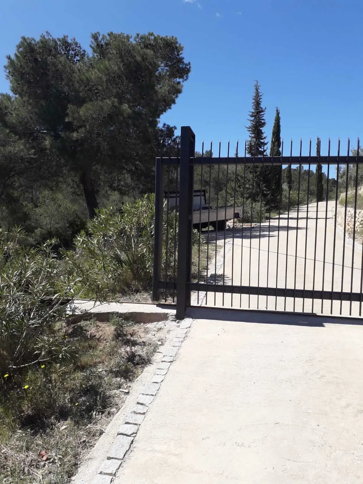 Construcción de puerta y cercado, para una casa de montaña, formada por acero pintado en forja