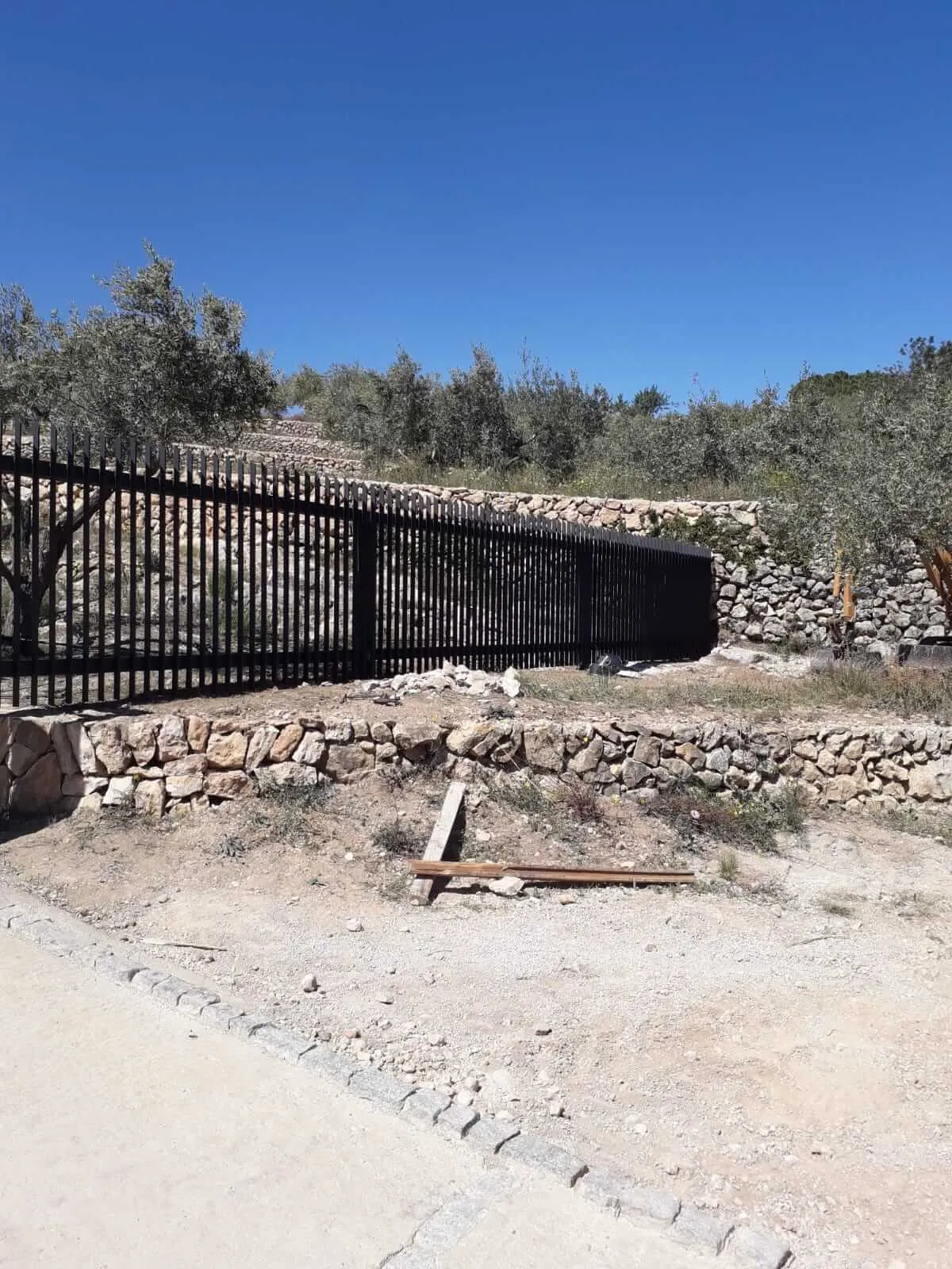Construcción de puerta y cercado, para una casa de montaña, formada por acero pintado en forja