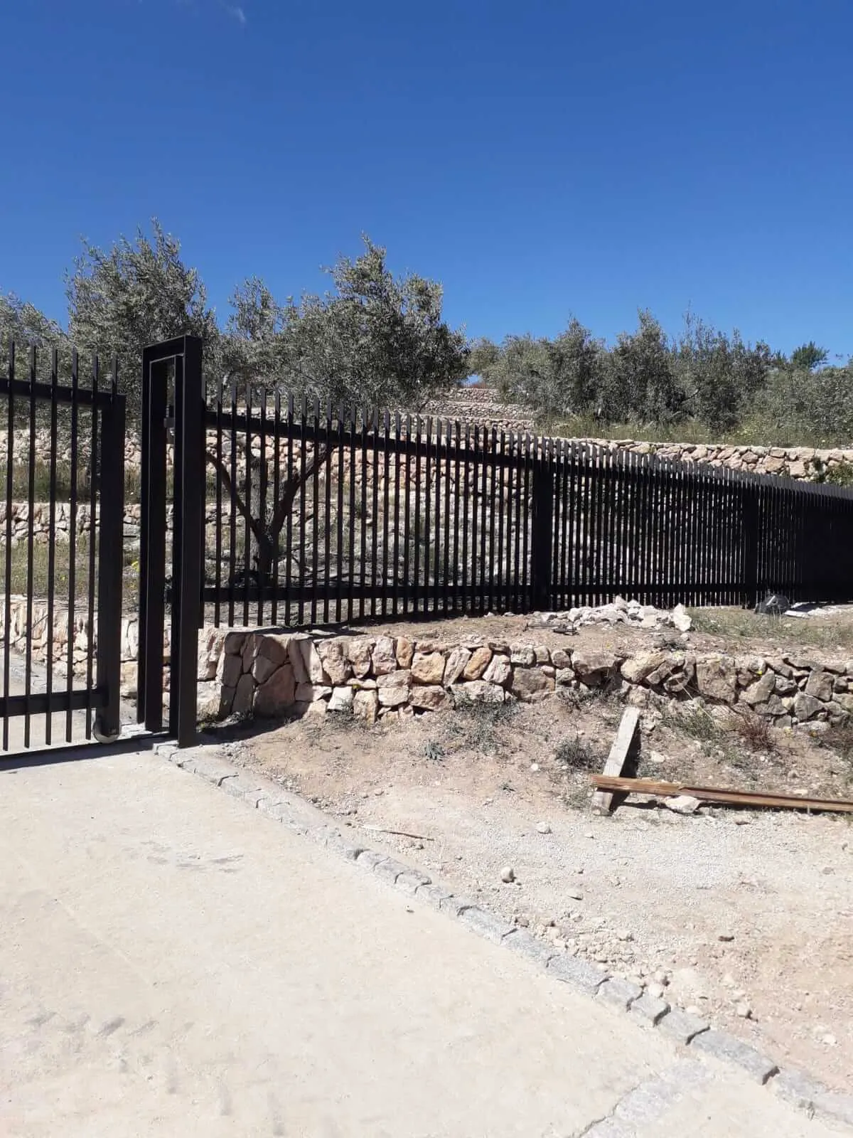 Construcción de puerta y cercado, para una casa de montaña, formada por acero pintado en forja